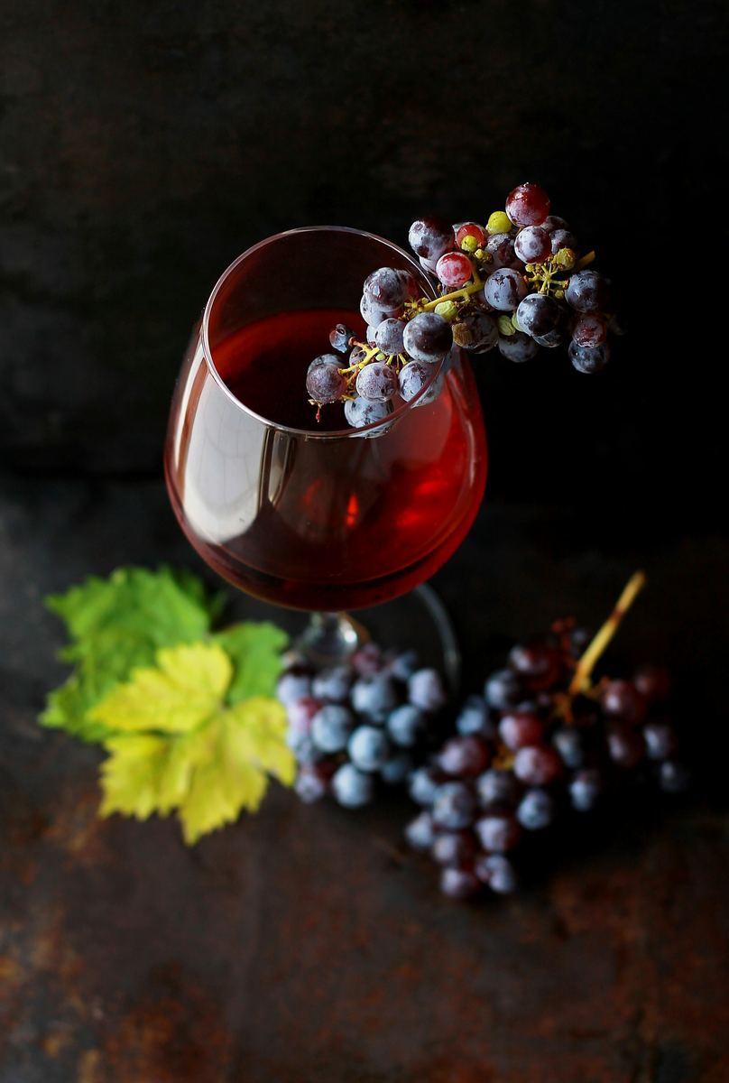 Calice di vino rosso accanto a un grappolo d'uva