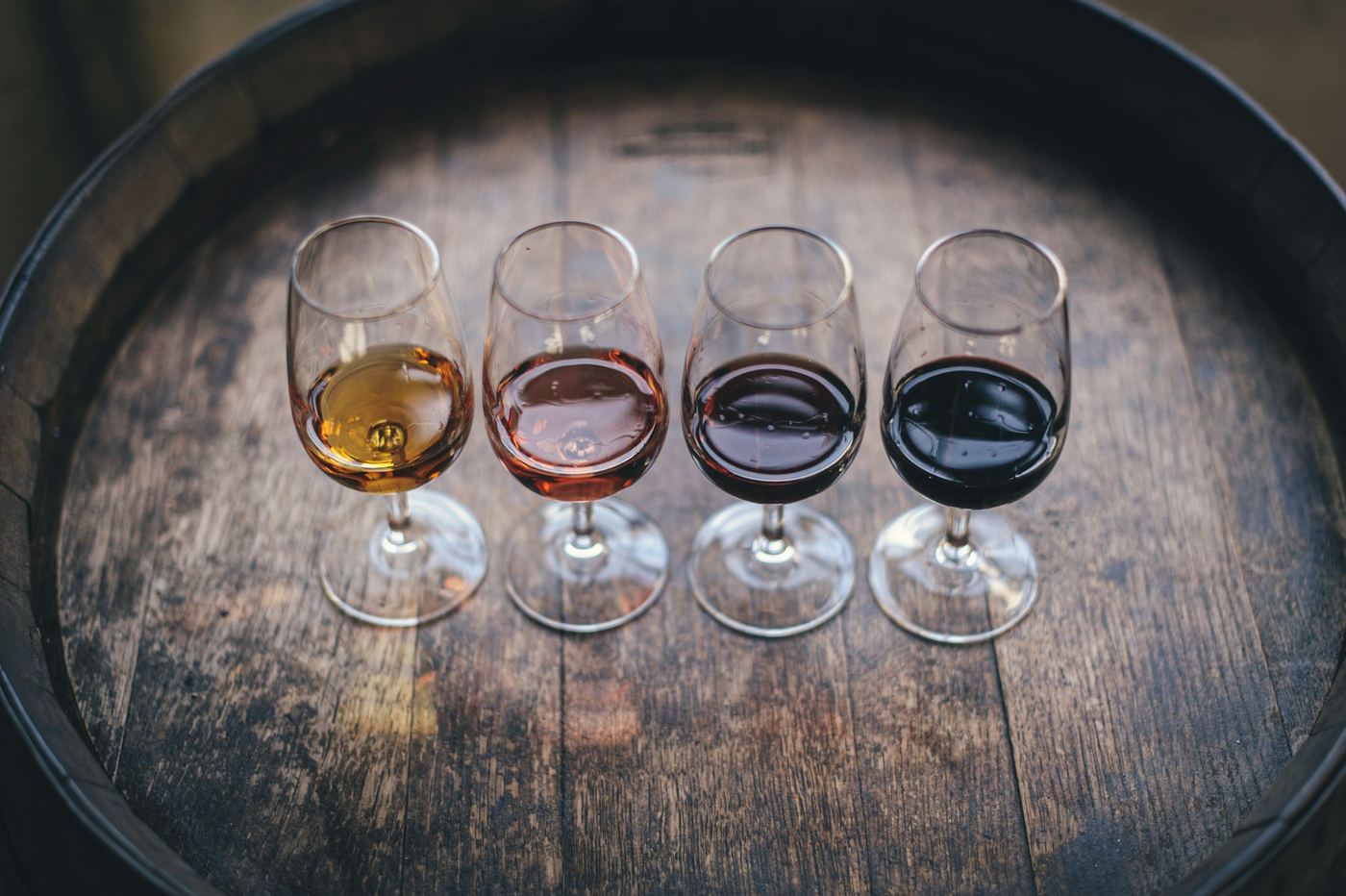Quattro calici con vini diversi su una botte di legno