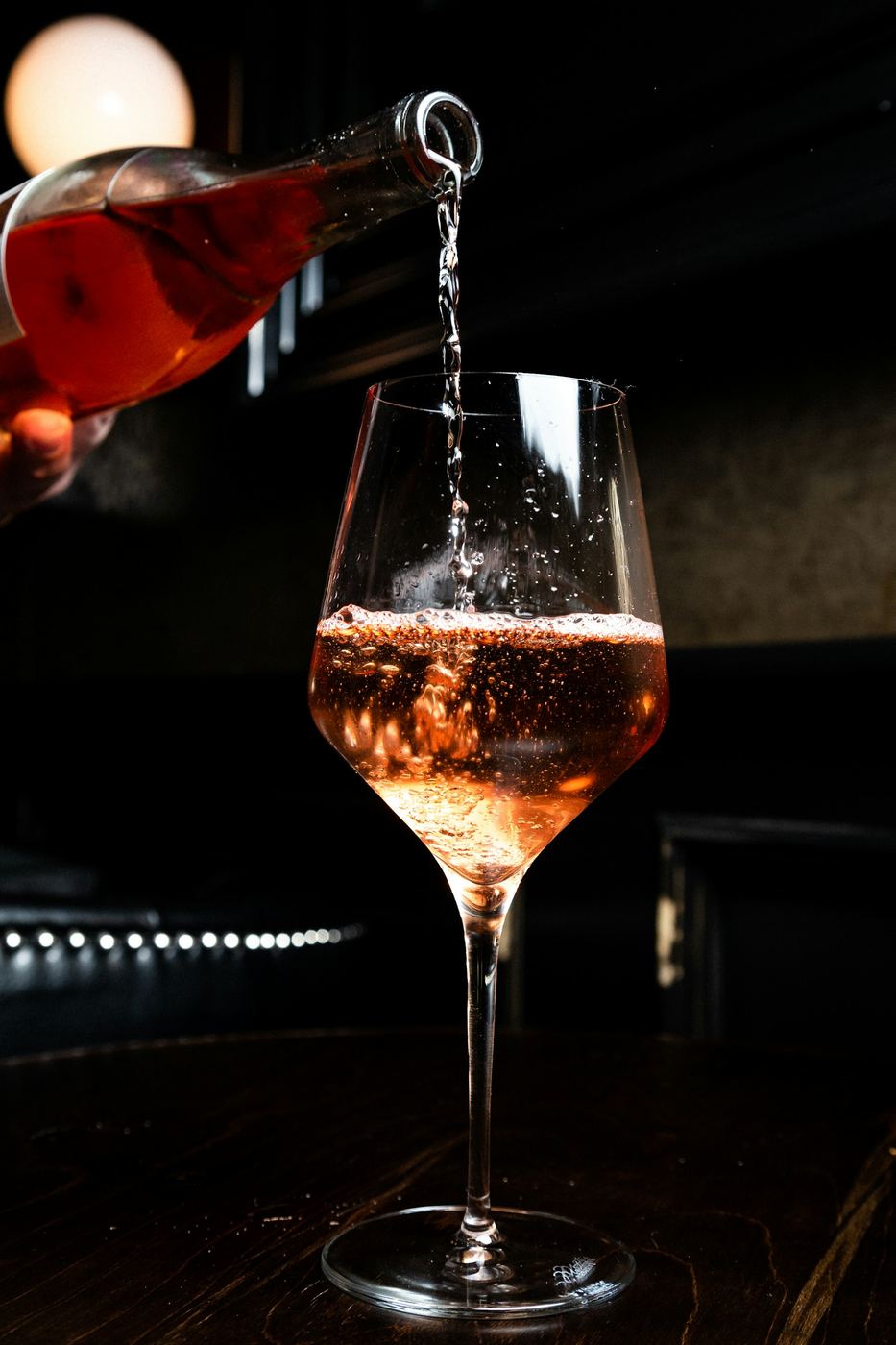 Vino rosso versato in un calice, in penombra